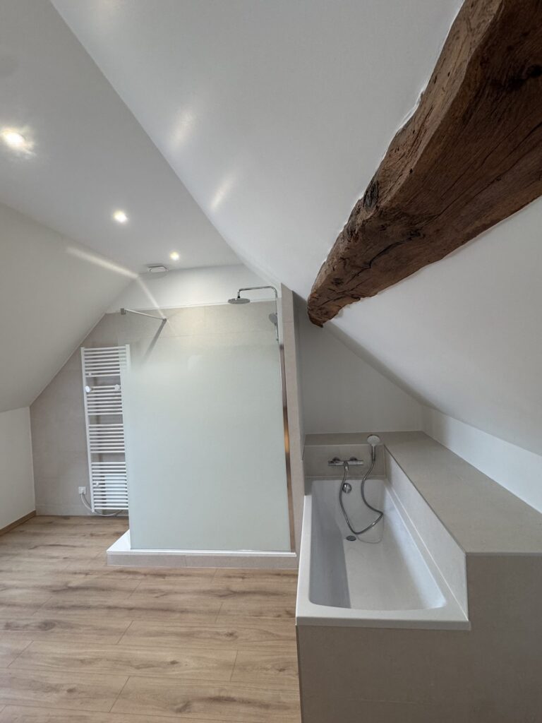 Douche et baignoire sous rampant dans une salle de bain aménagée sous combles