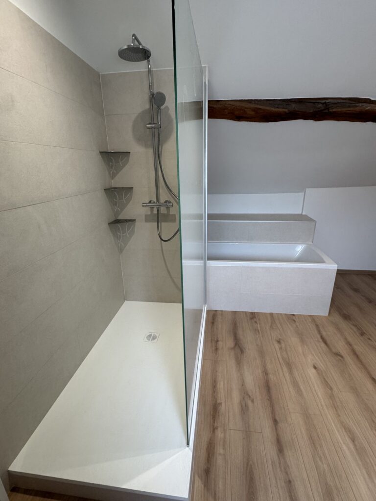 Douche à l'italienne et baignoire sous poutre apparente dans une salle de bain sous combles