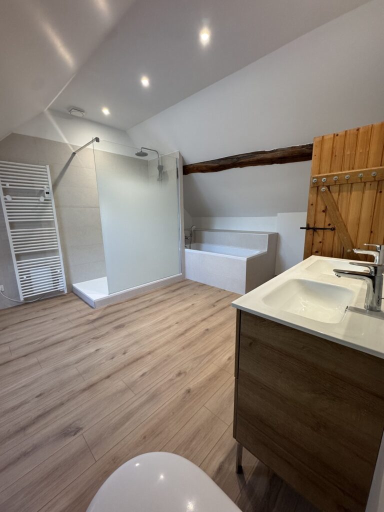 Baignoire et meuble vasque bois dans une salle de bain sous combles rénovée