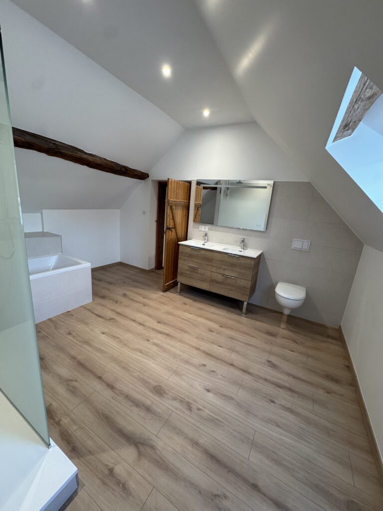 Vue d'ensemble d'une salle de bain sous combles rénovée avec meuble double vasque